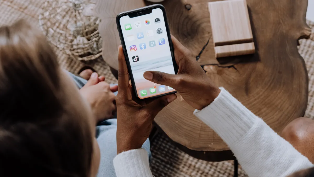 Pessoa usando smartphone com aplicativos de redes sociais na tela