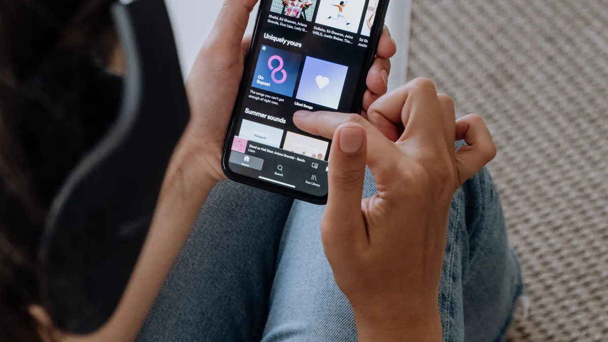 Pessoa usando smartphone e fones de ouvido para ouvir música